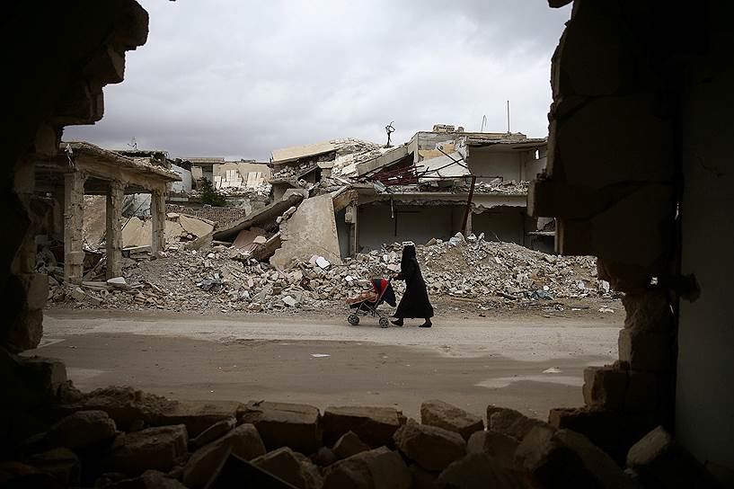 Дамаск, Сирия. Женщина с детской коляской на фоне разрушенных бомбардировками зданий