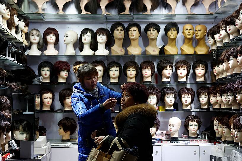 Шанхай, Китай. Продавец помогает покупателю примерить парик