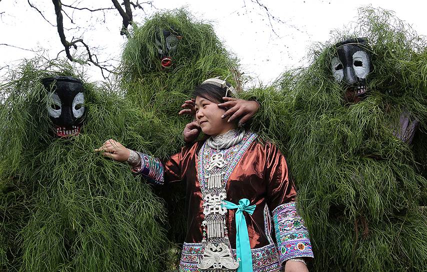 Лючжоу, Китай. Мужчины в традиционных карнавальных костюмах желают удачи местной жительнице во время празднования Китайского Нового года