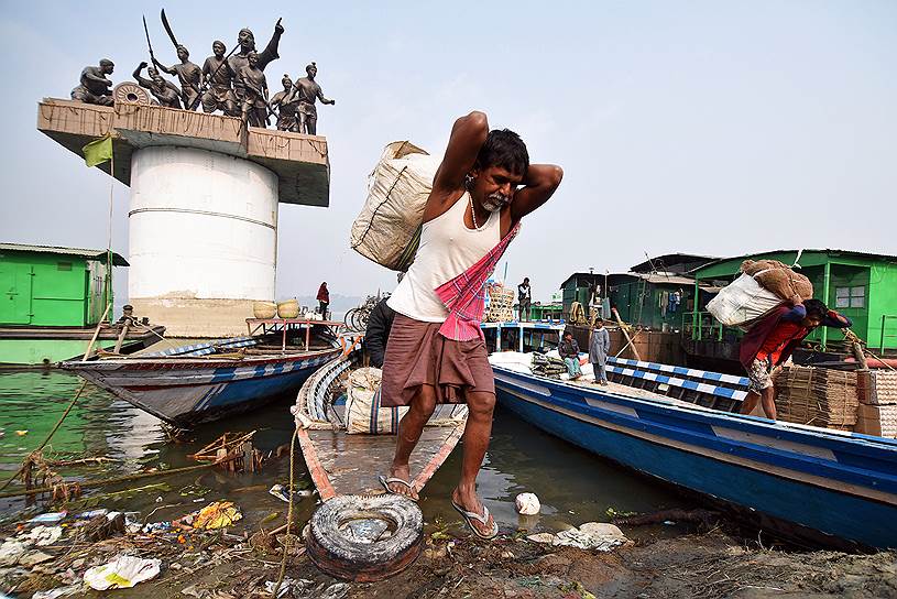 Гувахати, Индия. Торговец выгружает продукты из лодки на берегу реки Брахмапутра