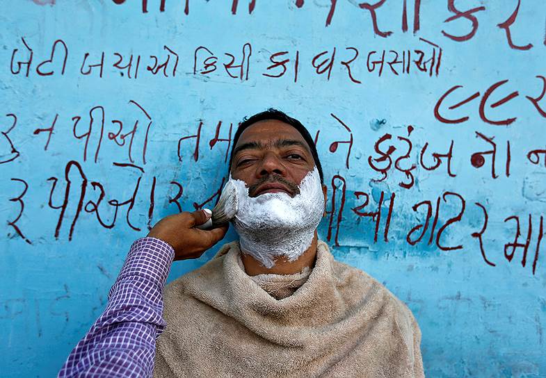 Ахмадабад, Индия. Мужчина во время бритья в придорожной парикмахерской 