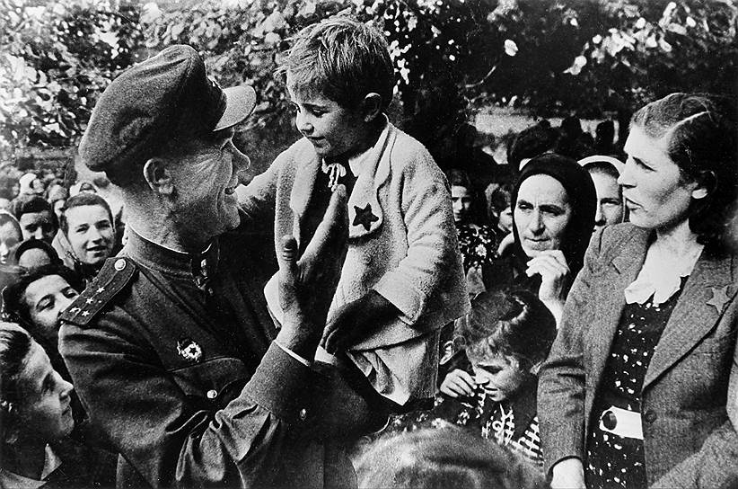 Гвардии капитан 109 стрелковой дивизии Степан Иванов с ребенком на руках в югославском селе, 1944