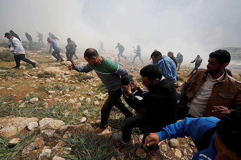 Рамалла, Палестина. Местные жители несут раненного во время столкновений с израильскими военными участника акции против еврейских поселений в окрестностях города
