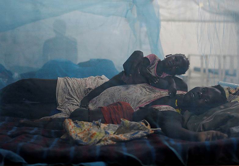 Бентиу, Южный Судан. Женщина с детьми лежит в постели в детском отделении больницы организации «Врачи без границ», расположенной на территории базы миссии ООН в Южном Судане (UNMISS)