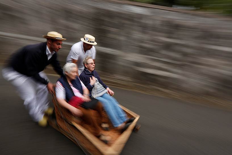 Фуншал, Португалия. Туристы едут с горы в специальном коробе на колесах