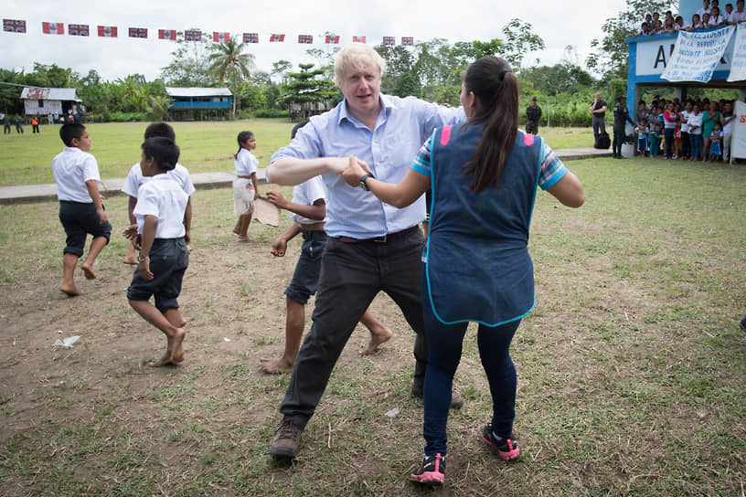 Премьер-министр Великобритании Борис Джонсон танцует с воспитательницей младших классов во время визита в Перу