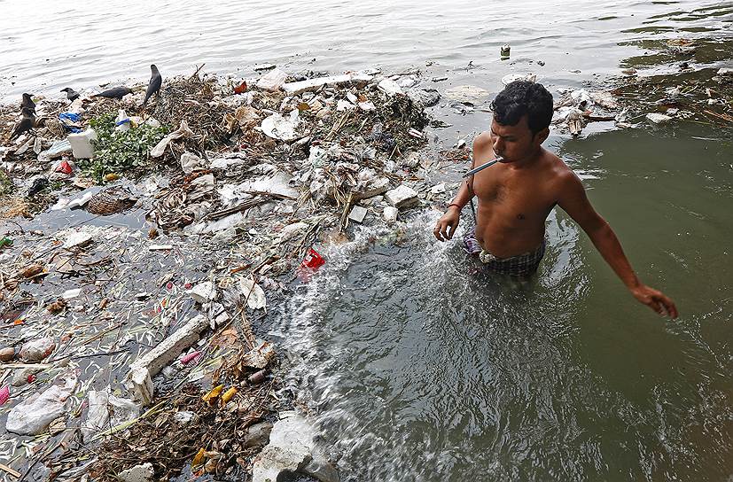 Калькутта, Индия. Мужчина чистит зубы в загрязненной реке Ганг 