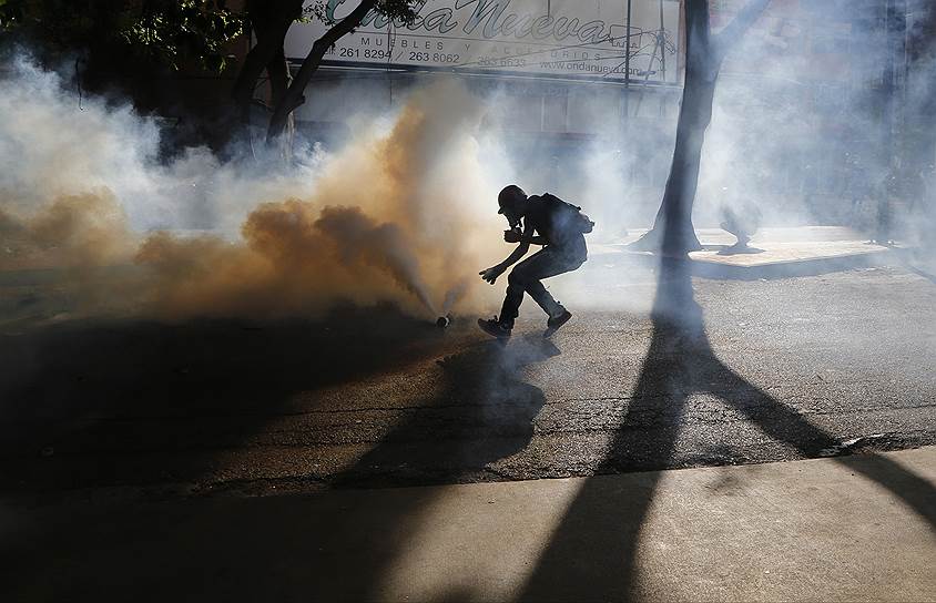 Каракас, Венесуэла. Участник антиправительственной акции, для разгона которой полицейские выпустили слезоточивый газ