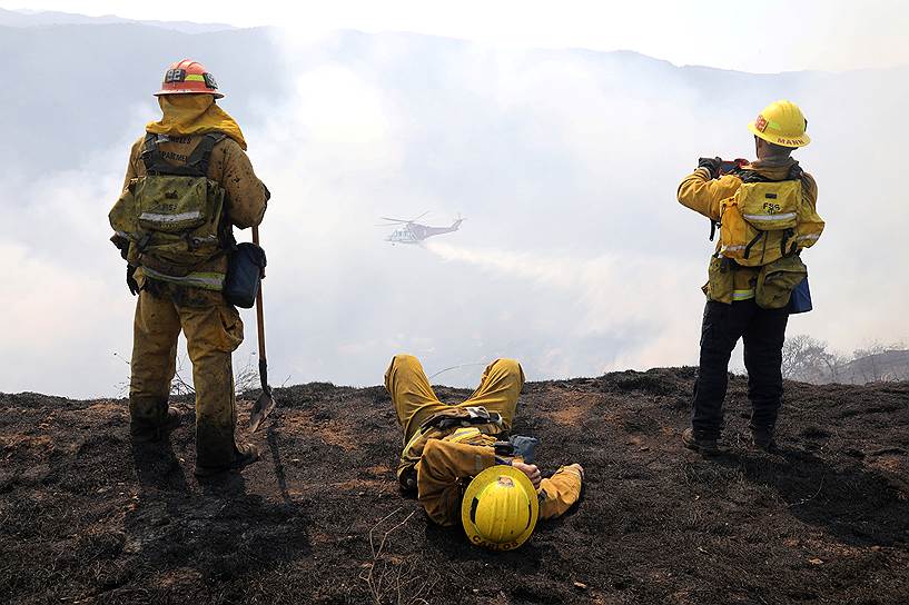 Лос-Анджелес, США. Пожарные смотрят как вертолет тушит лесной пожар 