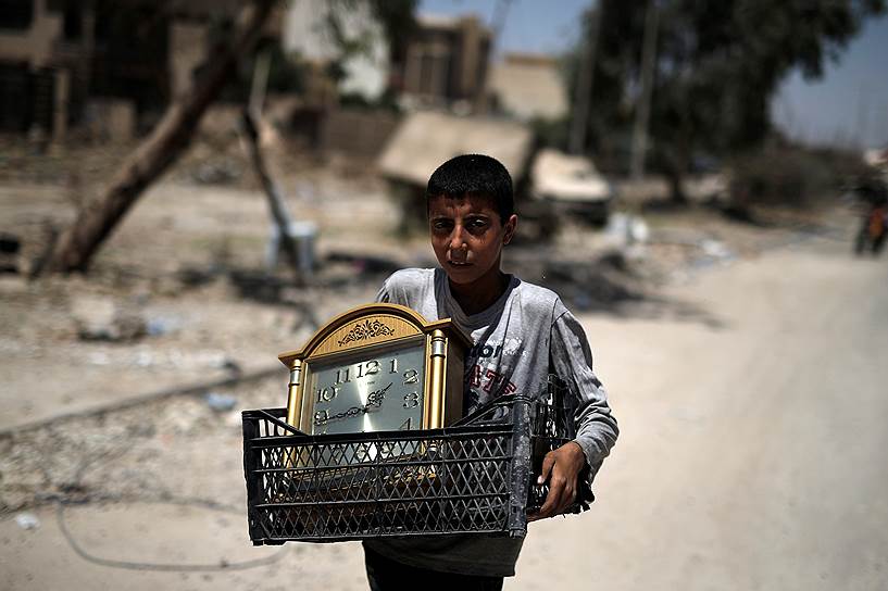Мосул, Ирак. Мальчик несет часы, которые нашел в западной части города