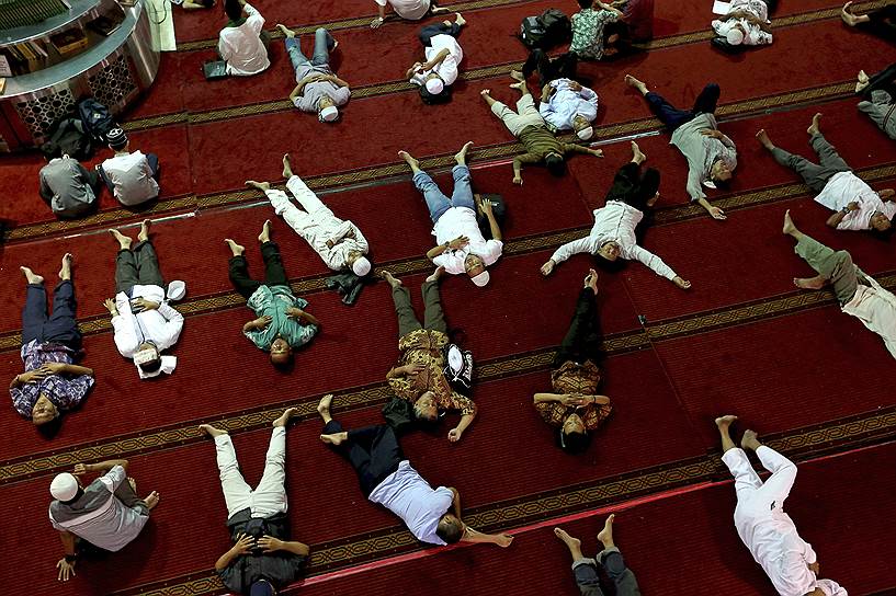 Джакарта, Индонезия. Мужчины-мусульмане дремлют в ожидании вечернего разговения после пятничной молитвы в мечети Истикляль