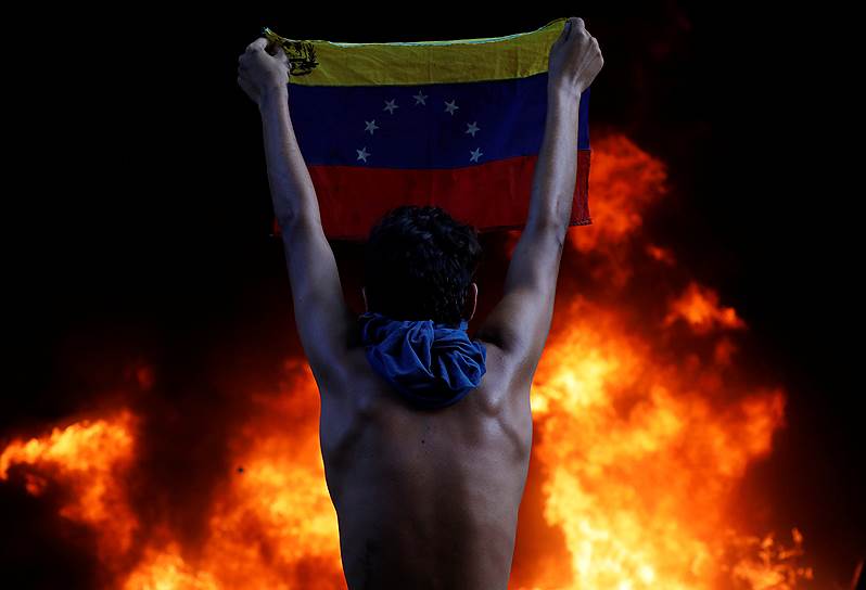 Каракас, Венесуэла. Демонстрант с флагом страны во время акции против политики президента Николаса Мадуро 