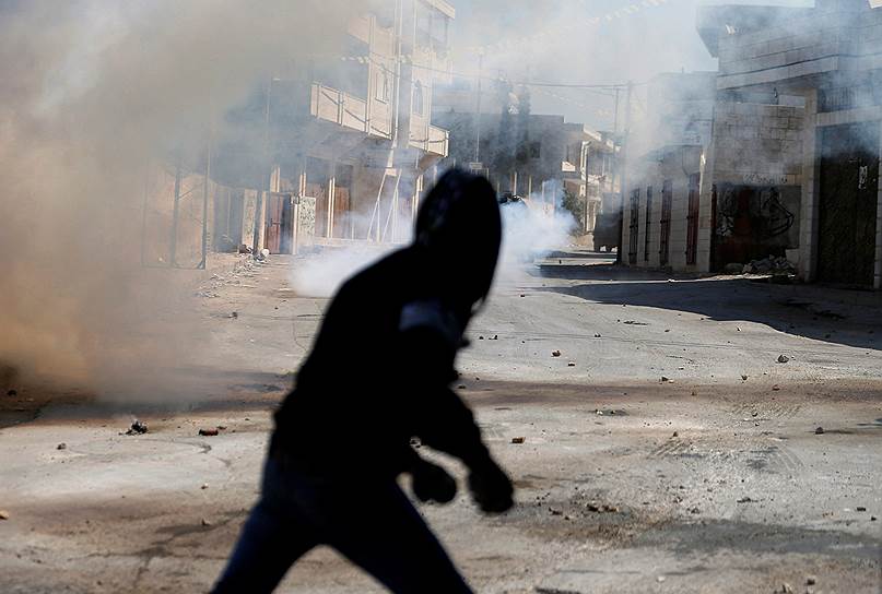 Рамалла, Западный берег реки Иордан. Палестинец укрывается от слезоточивого газа, распыленного израильскими военными во время рейда