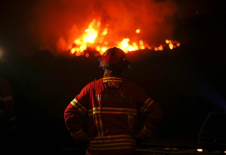 Центральная Португалия. Пожарный смотрит на горящий лес