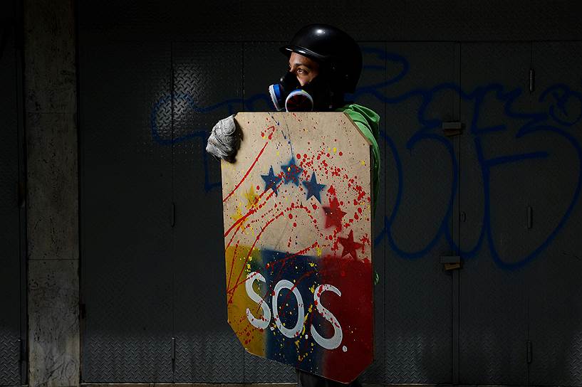 Знак SOS на одежде и щитах демонстрантов — это призыв к мировому сообществу обратить внимание на социально-экономическое положение Венесуэлы. В 2016 году Центробанк заявил, что инфляция составила 800%. Страна погрузилась в продовольственный кризис