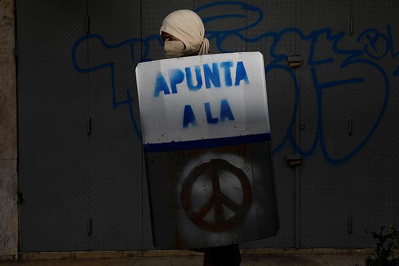 На щите демонстранта изображен международный символ мира и подпись: «Цель»