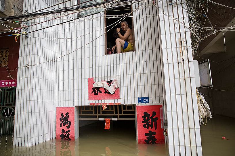 Чжаоцин, Китай. Мужчина спасается от наводнения на чердаке дома