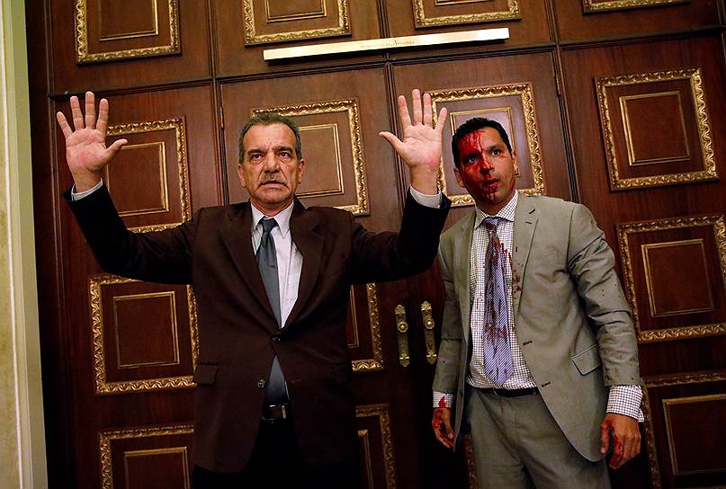 Каракас, Венесуэла. Оппозиционный законодатель Луис Стефанелли (слева) показывает, что он сдается, после того как группа сторонников правительства ворвалась в контролируемый оппозицией парламент страны
