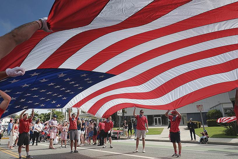Санта-Моника, штат Калифорния. Участники парада несут американский флаг во время празднования Дня незавосимости