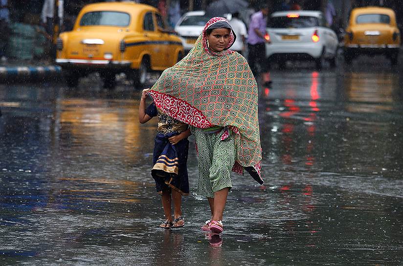 Калькутта, Индия. Женщина прикрывает свою дочь от дождя