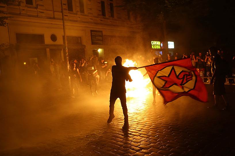 Протестующие размахивают флагами и поджигают мусор на площади города