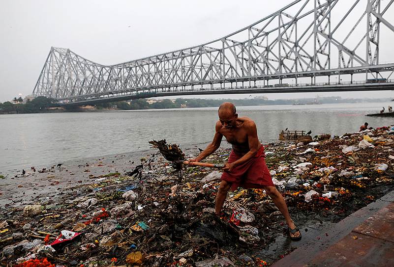 Пляж реки Ганг в городе Калькутта завален мусором. Несмотря на это, люди купаются в воде, пьют ее и чистят там зубы