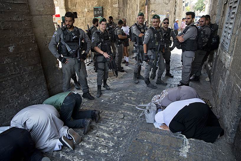 Старый город (Иерусалим), Израиль. Палестинцы молятся, в то время как офицеры пограничной полиции Израиля охраняют Львиные ворота