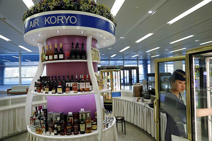 Продавец расставляет напитки в баре Air Koryo в аэропорту Пхеньяна