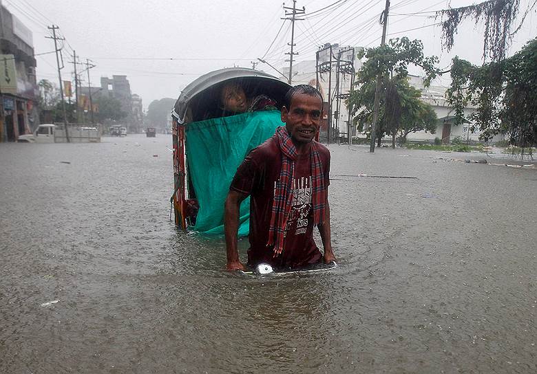 Агартала, Индия. Человек везет рикшу по затопленной улице