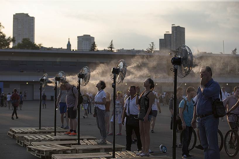 Москва, Россия. Люди стоят у вентиляторов в жаркий день