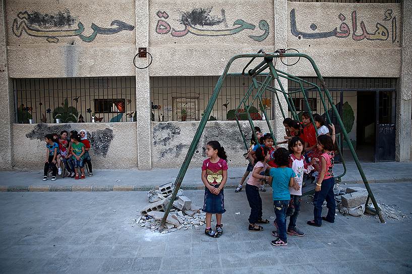 Дамаск, Сирия. Дети играют на качелях на школьной площадке