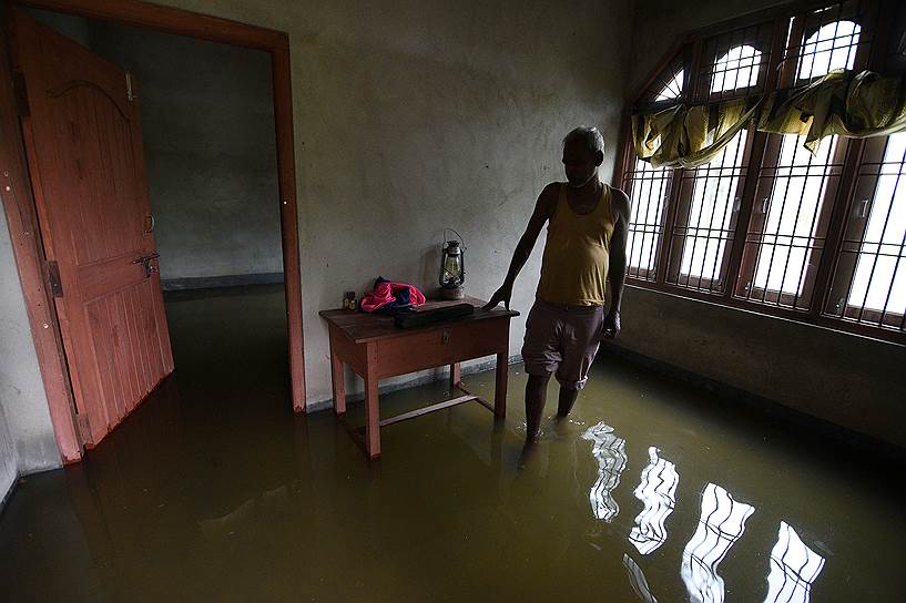 Ассам, Индия. Мужчина стоит посреди своего частично затопленного дома