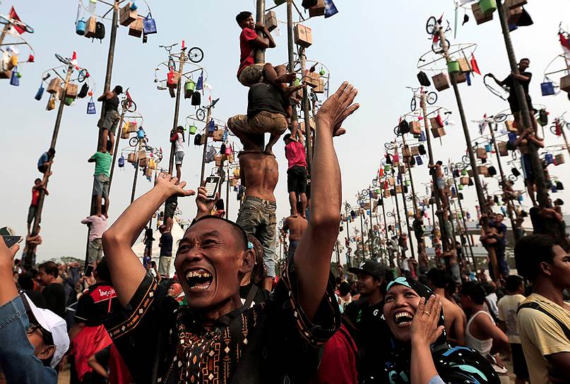 Джакарта, Индонезия. Люди радуются победе и выигрышу велосипеда своим коллегой в ходе соревнований по залезанию на столб в ходе празднования Дня независимости