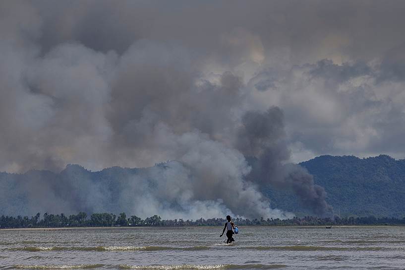 Шах Порир Двип, Бангладеш. Мальчик идет к пришвартованной лодке на фоне дыма над границей с Мьянмой