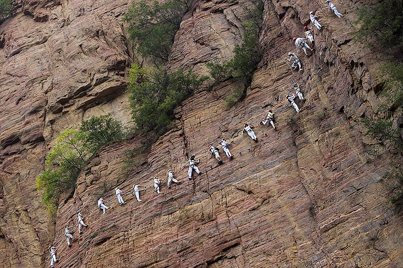 Лоян, провинция Хэнань, Китай. Люди, поднимающиеся по скале с помощью веревки