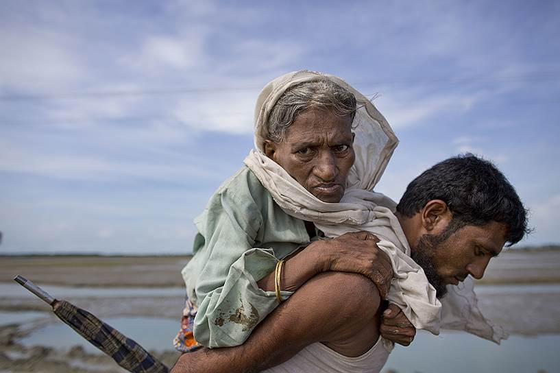 Текнаф, Бангладеш. Мусульманин-рохинджа помогает женщине добраться до лагеря беженцев