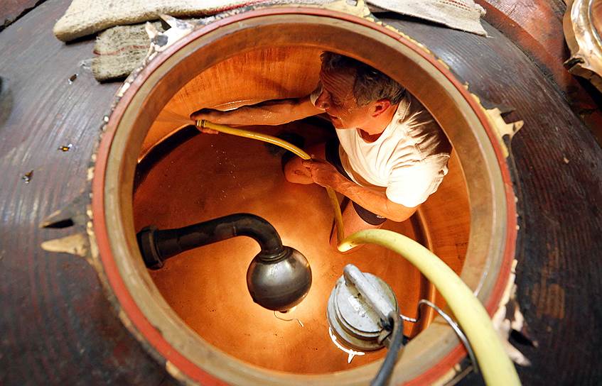 Шатонеф-сюр-Шарант, Франция. Рабочий чистит медный перегонный куб на винокуренном заводе Courvoisier