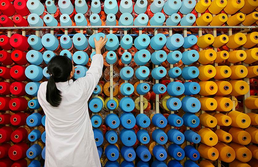 Хайань, Китай. Работница текстильной фабрики наматывает нитки на катушки 