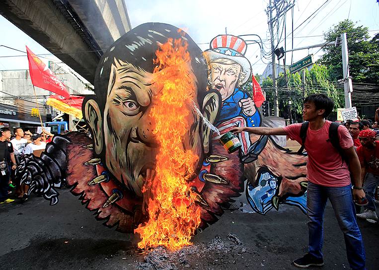 Манила, Филиппины. Протестующий сжигает изображения президентов Филиппин и США Родриго Дутерте и Дональда Трампа на акции протеста  