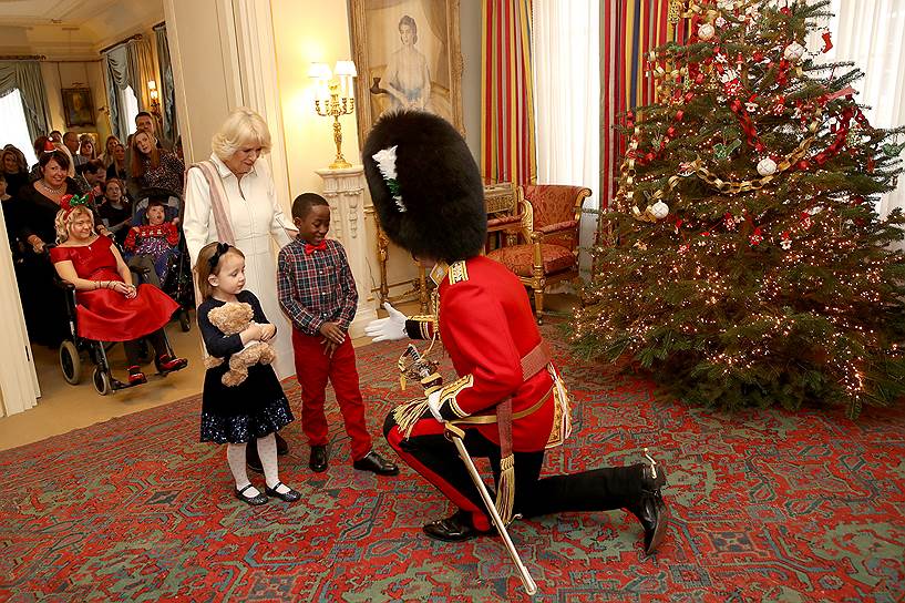 Лондон, Великобритания. Королевский гвардеец и герцогиня Корнуольская Камилла приветствуют детей в Кларенс-хаусе