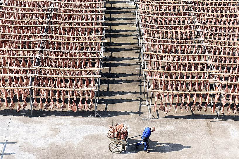 Цзиньхуа, Китай. Рабочий везет телегу с окороками