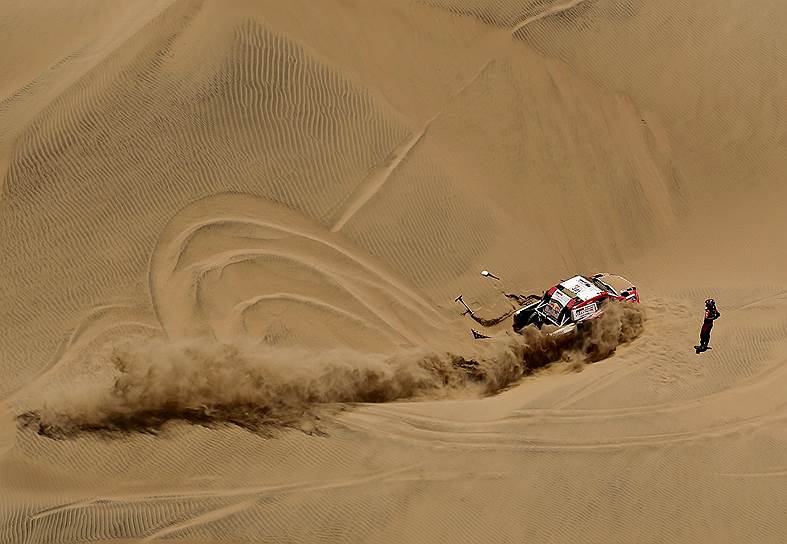 Сан-Хуан-де-Маркона, Перу. Автогонщики Насер Салех аль-Атыйи (Катар) и Матье Баумель (Франция) пытаются сдвинуть застрявший в песках внедорожник Toyota во время гонки «Дакар»