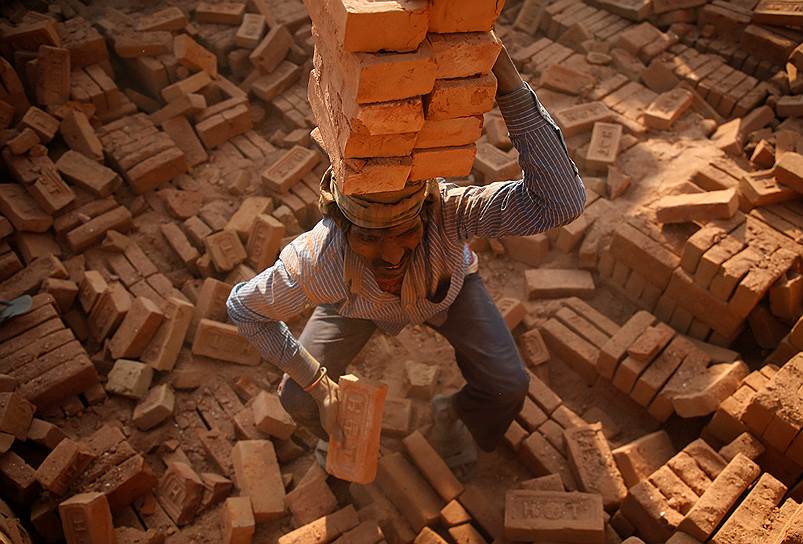 Бхактапур, Непал. Рабочий кирпичного завода грузит камень 