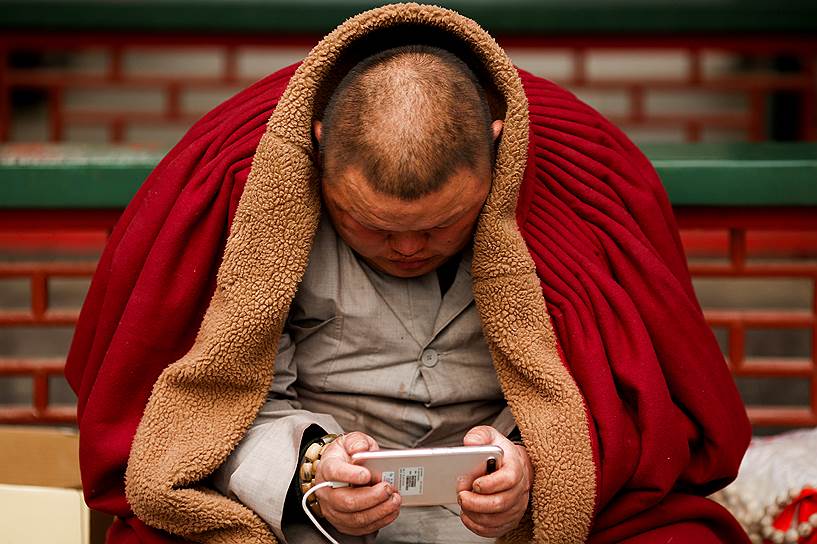 Пекин, Китай. Местный житель пользуется телефоном во время торжественных мероприятий в честь китайского Нового года в парке Бадачу 