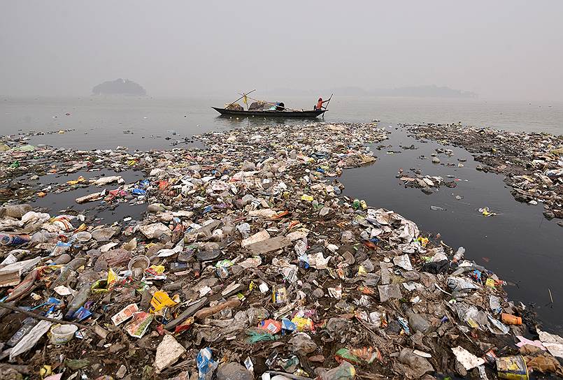 Гувахати, Индия. Местный житель плывет на лодке по загрязненной реке Брахмапутра