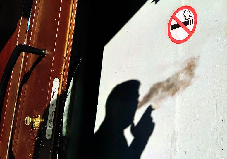 Москва. Тень курящего мужчины рядом со знаком «Курение запрещено»