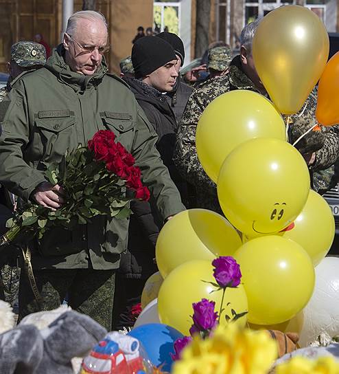 Председатель Следственного комитета России Александр Бастрыкин (в центре) во время посещения стихийного мемориала из цветов и игрушек в память о жертвах пожара в торговом центре