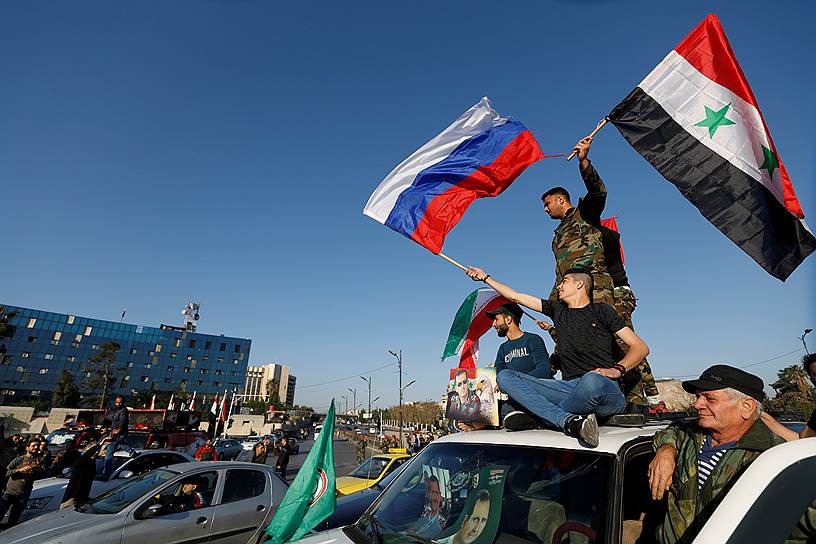 Сирийцы с российскими и сирийскими флагами во время акции протеста против авиаударов США в Дамаске