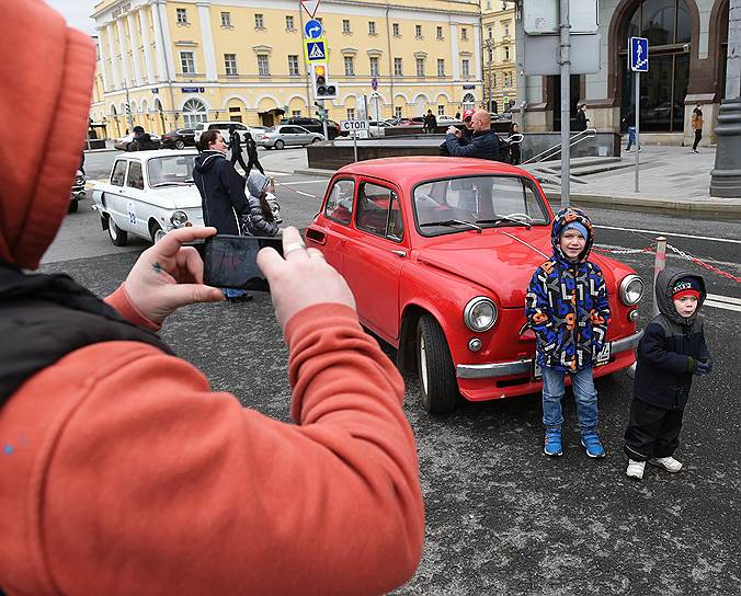 Дети фотографируются рядом с красным ретро-автомобилем