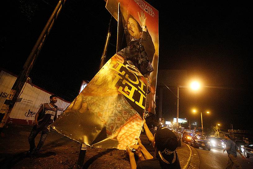 Протестующие рвут рекламные щиты с изображением президента страны